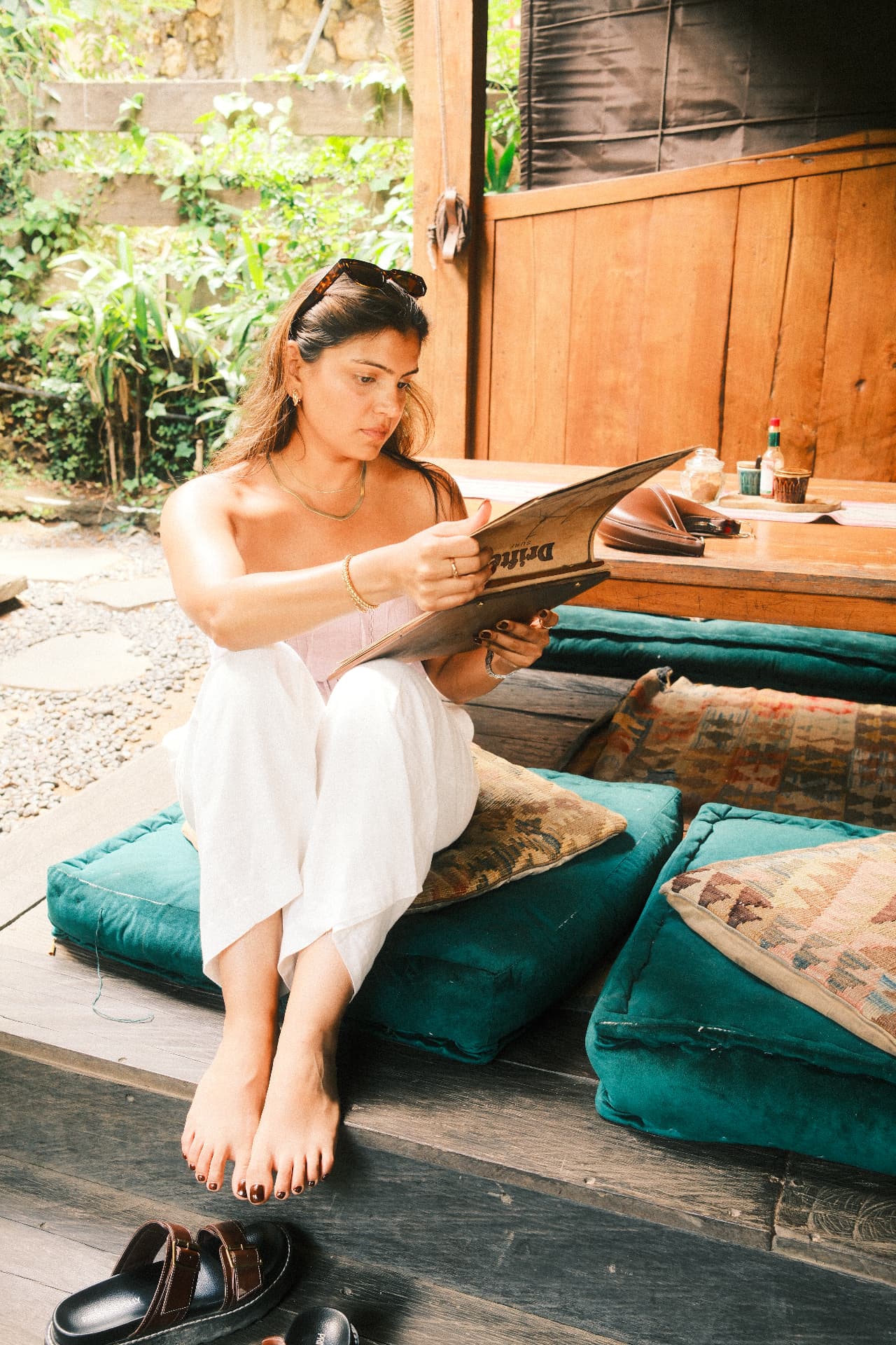 Dr. Jill Thaker sitting cross-legged on floor cushions, reading a menu at an outdoor café