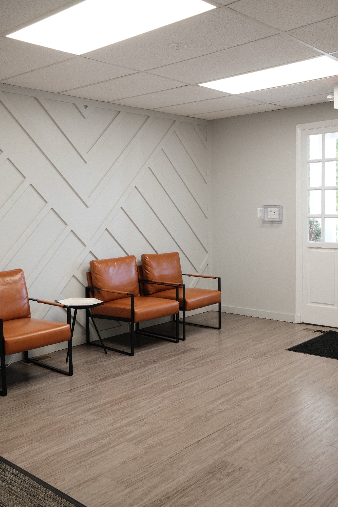Warm leather chairs beside a geometric white wall in the studio waiting area